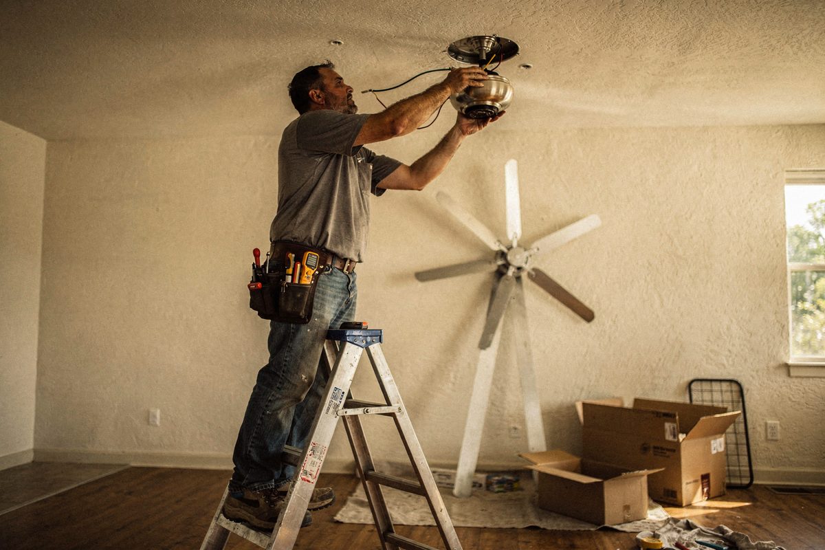 Electrician installing a ceiling fan on a fan-rated box